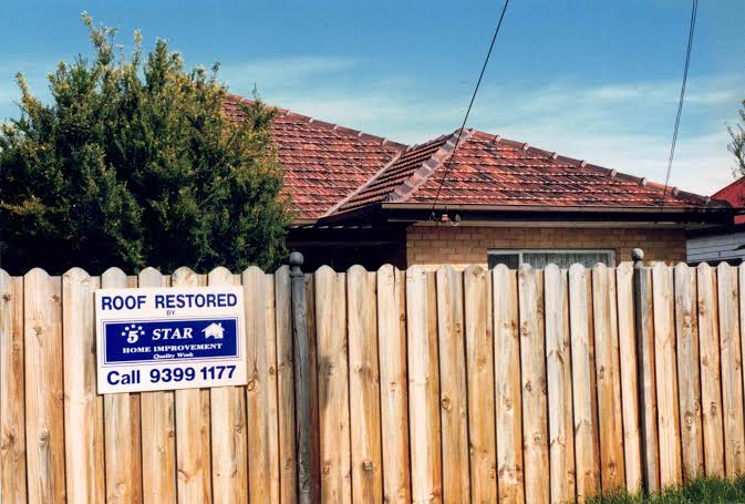 Tiled roof behind a timber fence with a 5 Star Home Improvement sign